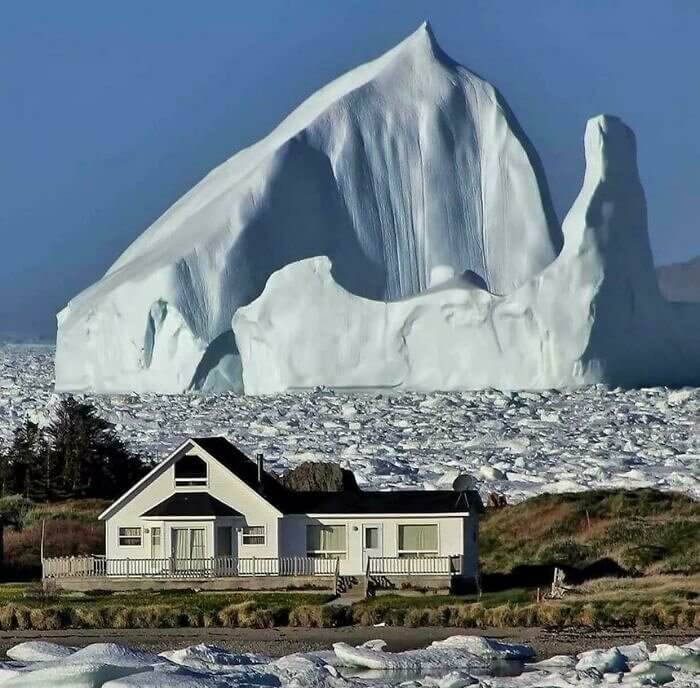 Iceberg Floating by a Small Town in Canada