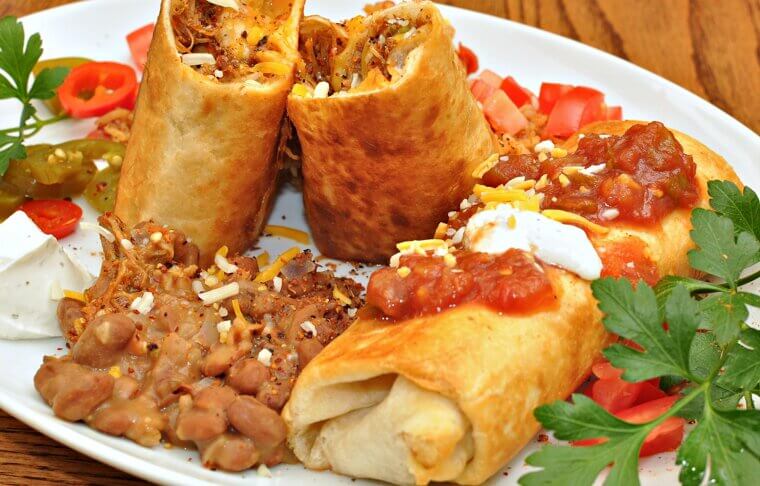A startled cook accidentally dropped a freshly rolled burrito into a vat of hot frying oil, delightfully inventing the crispy chimichanga